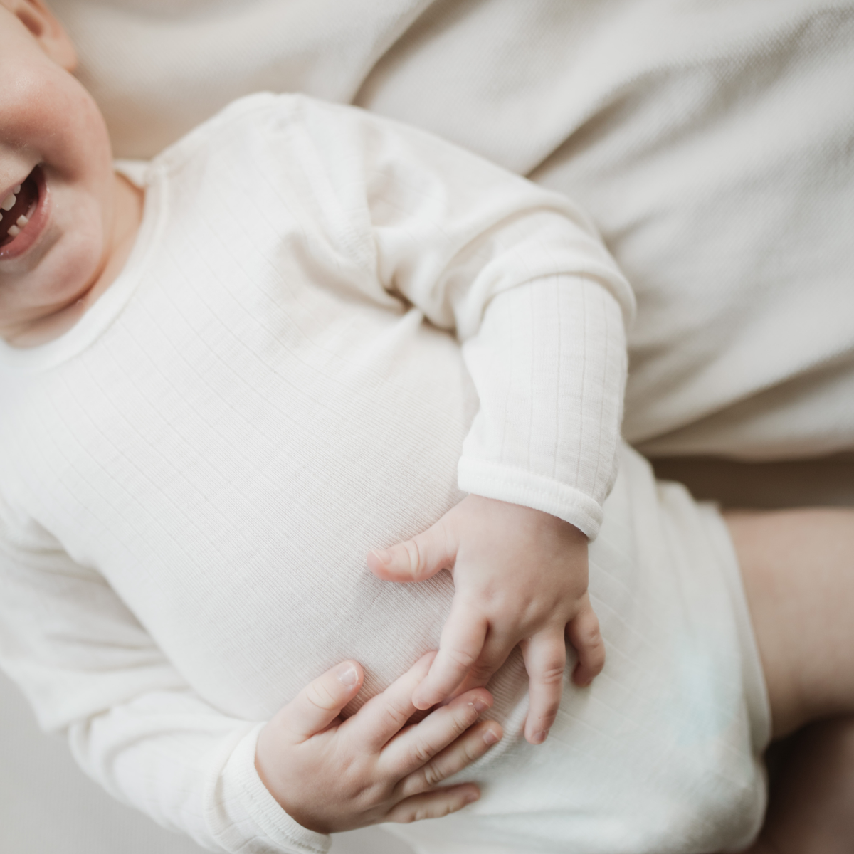 Baby im weißen Joha Langarmbody aus Wolle-Seide | SYNCSON